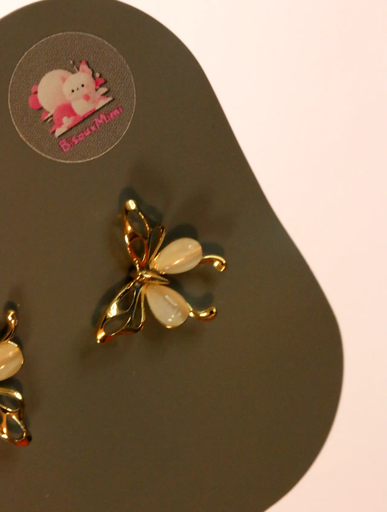Detalle de pendiente de mariposa dorado con detalles crema — pendientes baratos, detalle · Lola y Sol (24AE1008)