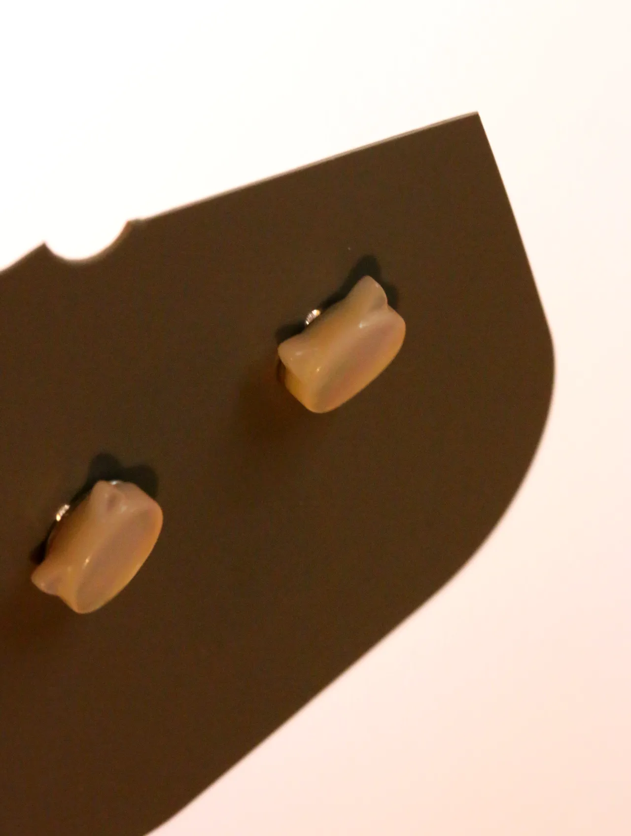 Detalle de los pendientes de gato en tono crema brillante — pendientes dorados, primer plano · Lola y Sol (24AE1015)