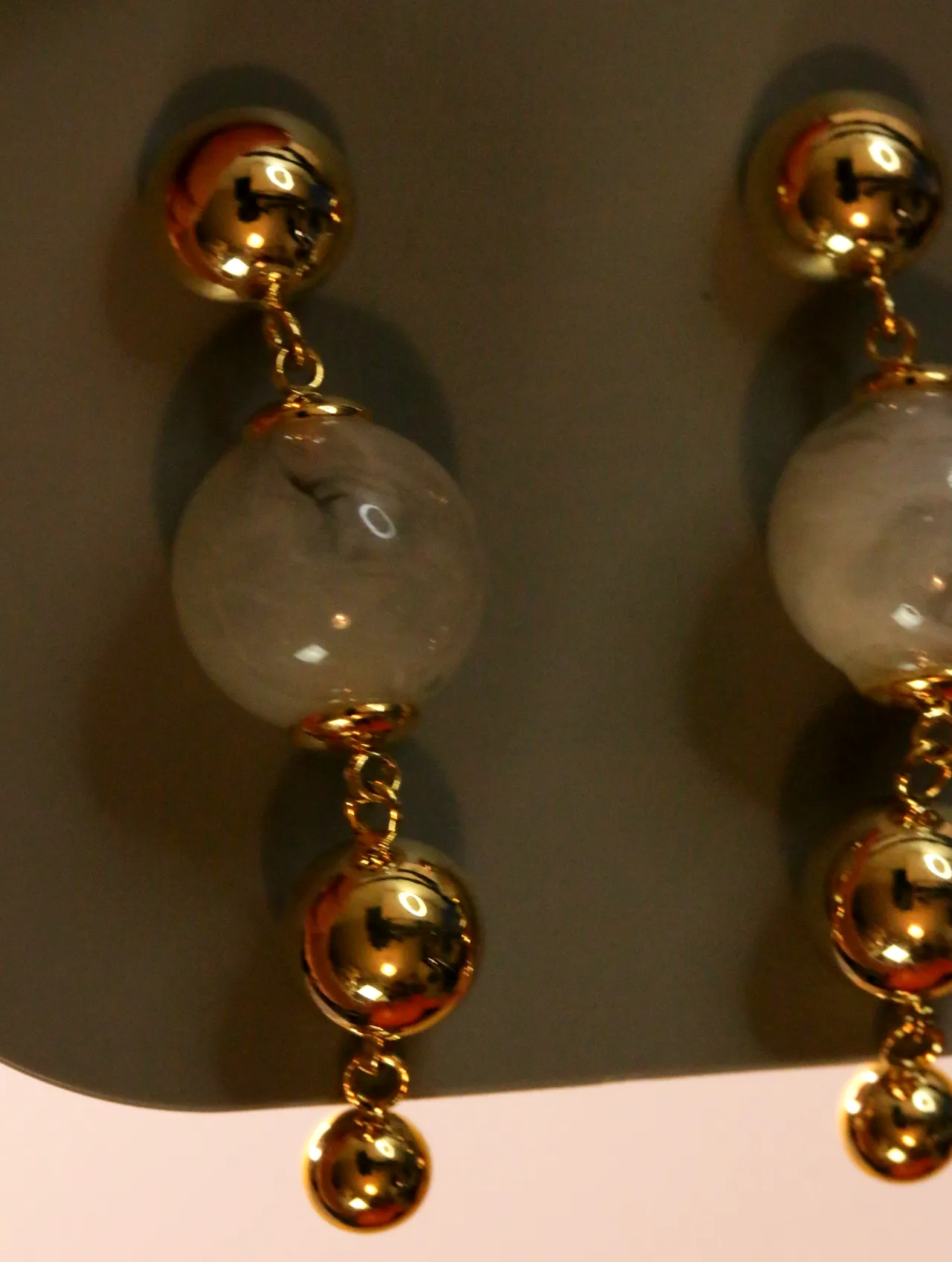 Detalle de esferas doradas brillantes y cuentas translúcidas lechosas — pendientes baratos, detalle · Lola y Sol (24AE1023)