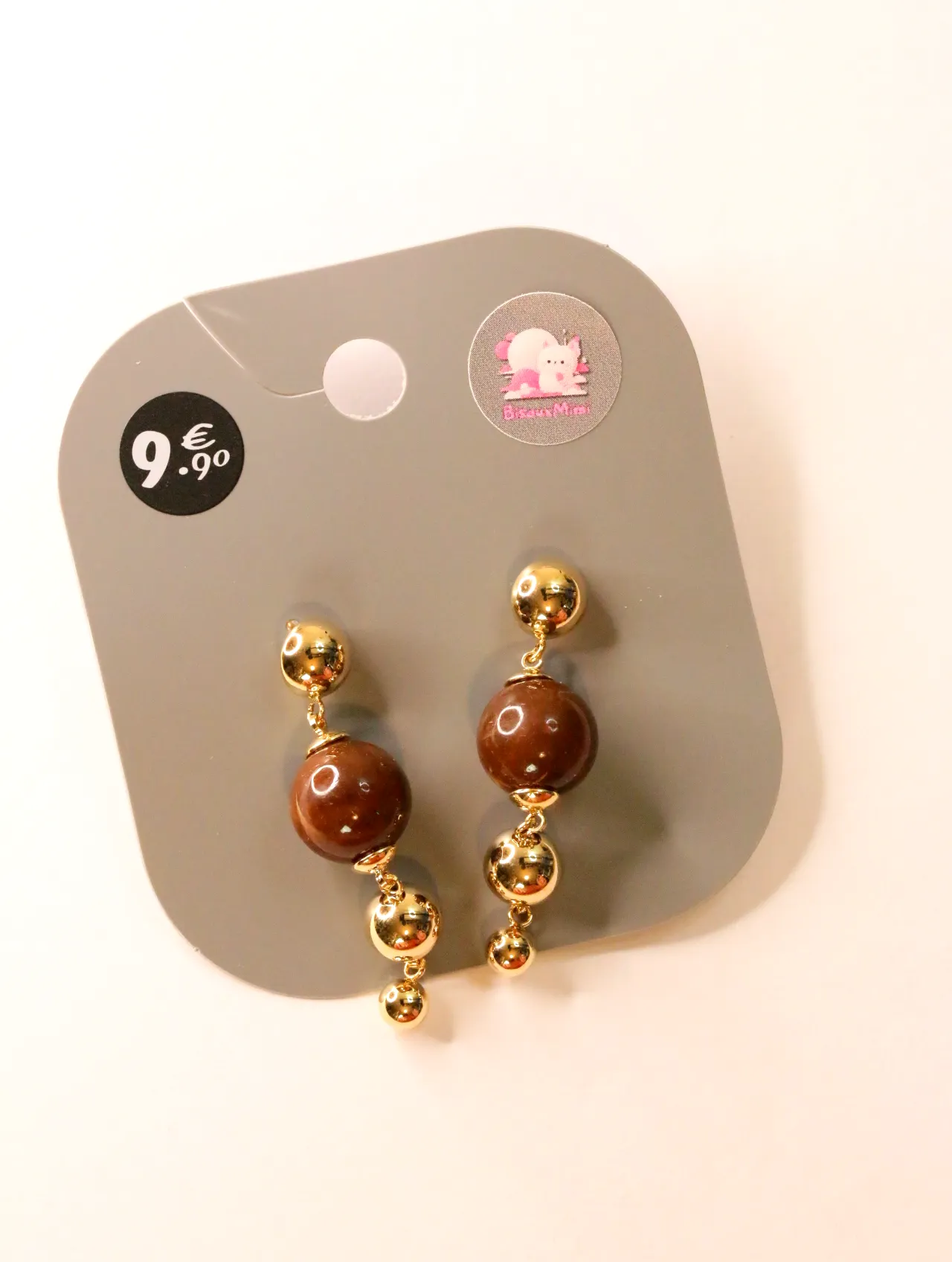 Pendientes largos dorados con cuentas marrones sobre tarjeta — pendientes para mujer, vista principal · Lola y Sol (24AE1029)