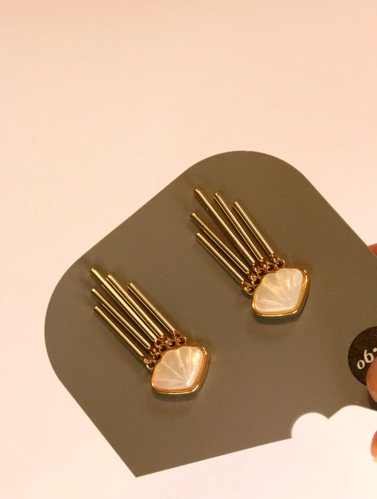 Detalle de pendientes dorados de flecos con adorno nacarado sobre tarjeta — pendientes para mujer, vista principal · Lola y Sol (24AE1052)