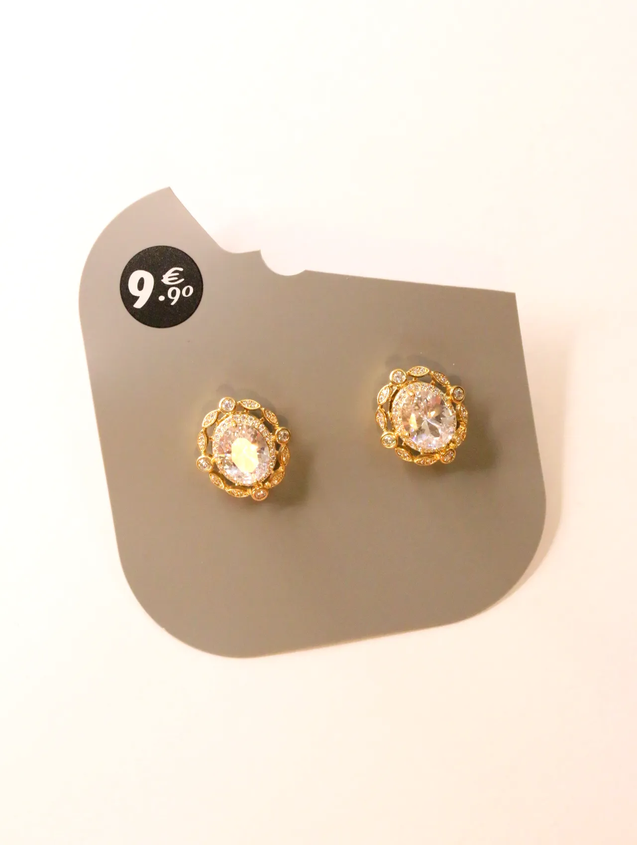 Pendientes ovalados dorados con centro transparente sobre tarjeta — pendientes de moda, vista lateral · Lola y Sol (24AE1088)