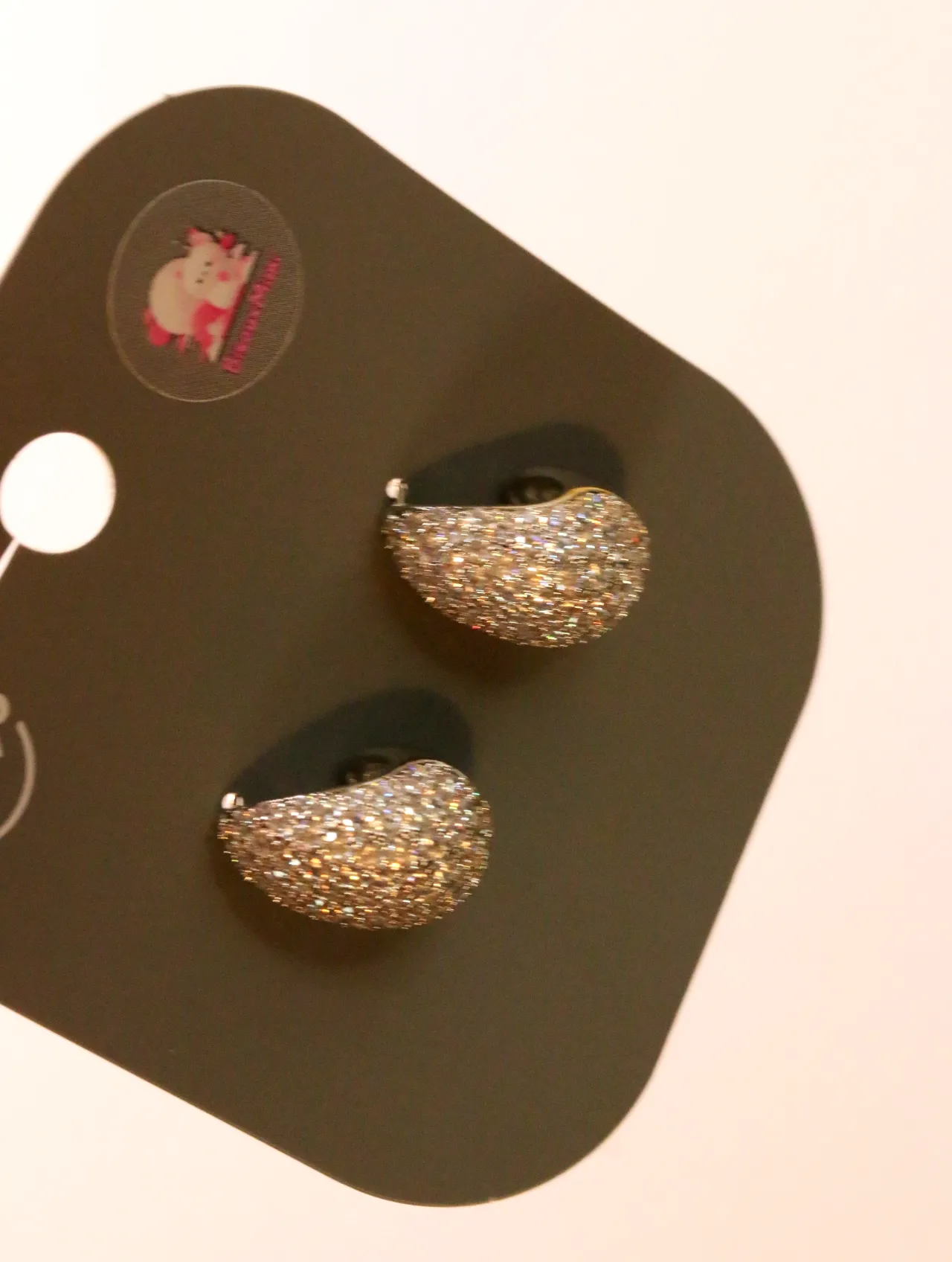 Detalle de los pendientes redondeados y su acabado brillante — pendientes baratos, puestos en la oreja · Lola y Sol (24AE1099)
