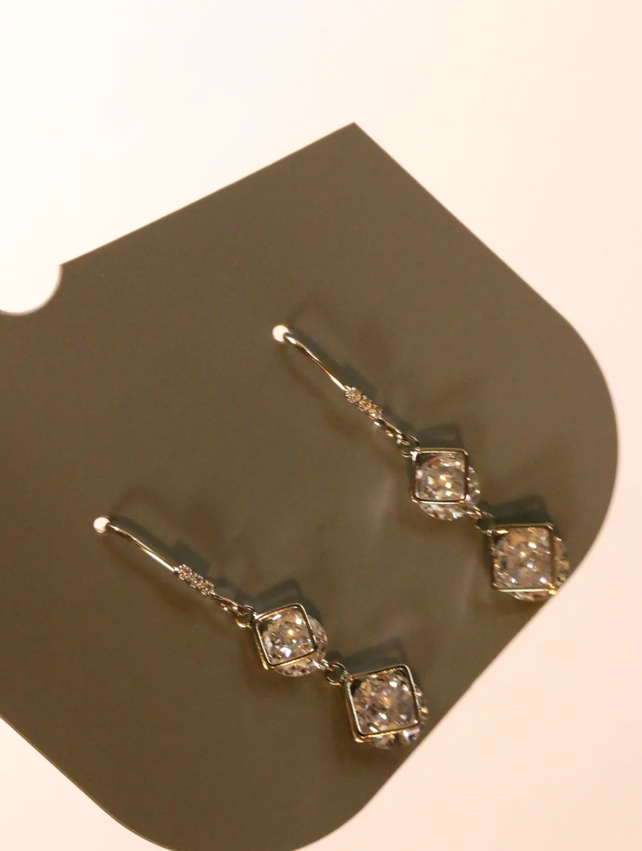 Detalle de los adornos geométricos brillantes de los pendientes plateados — pendientes dorados, primer plano · Lola y Sol (24AE1239)