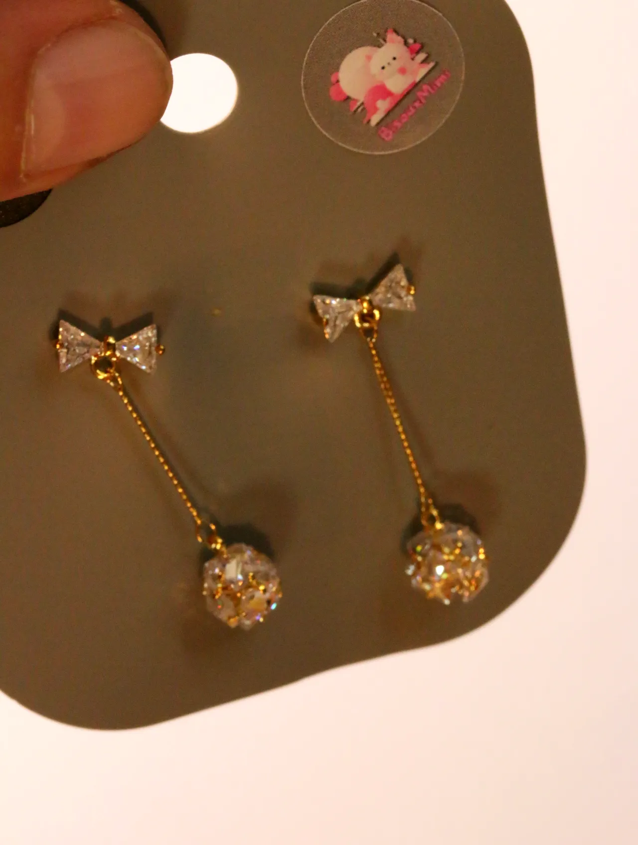 Detalle de los lazos brillantes y las bolas decorativas colgantes — pendientes baratos, detalle · Lola y Sol (24AE1243)