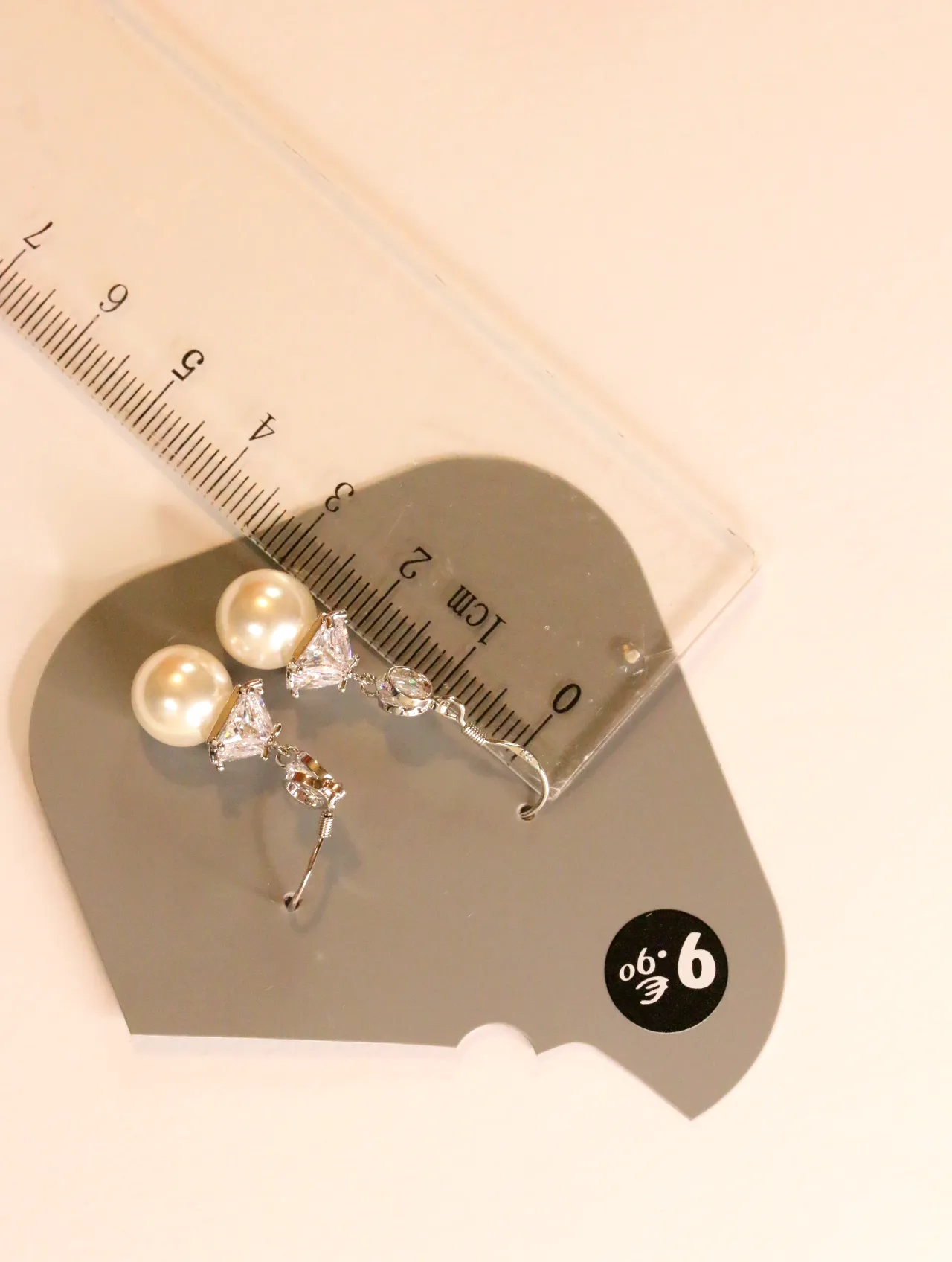 Pendientes con perlas de imitación en tarjeta junto a una regla — pendientes de moda, vista lateral · Lola y Sol (24AE1247)