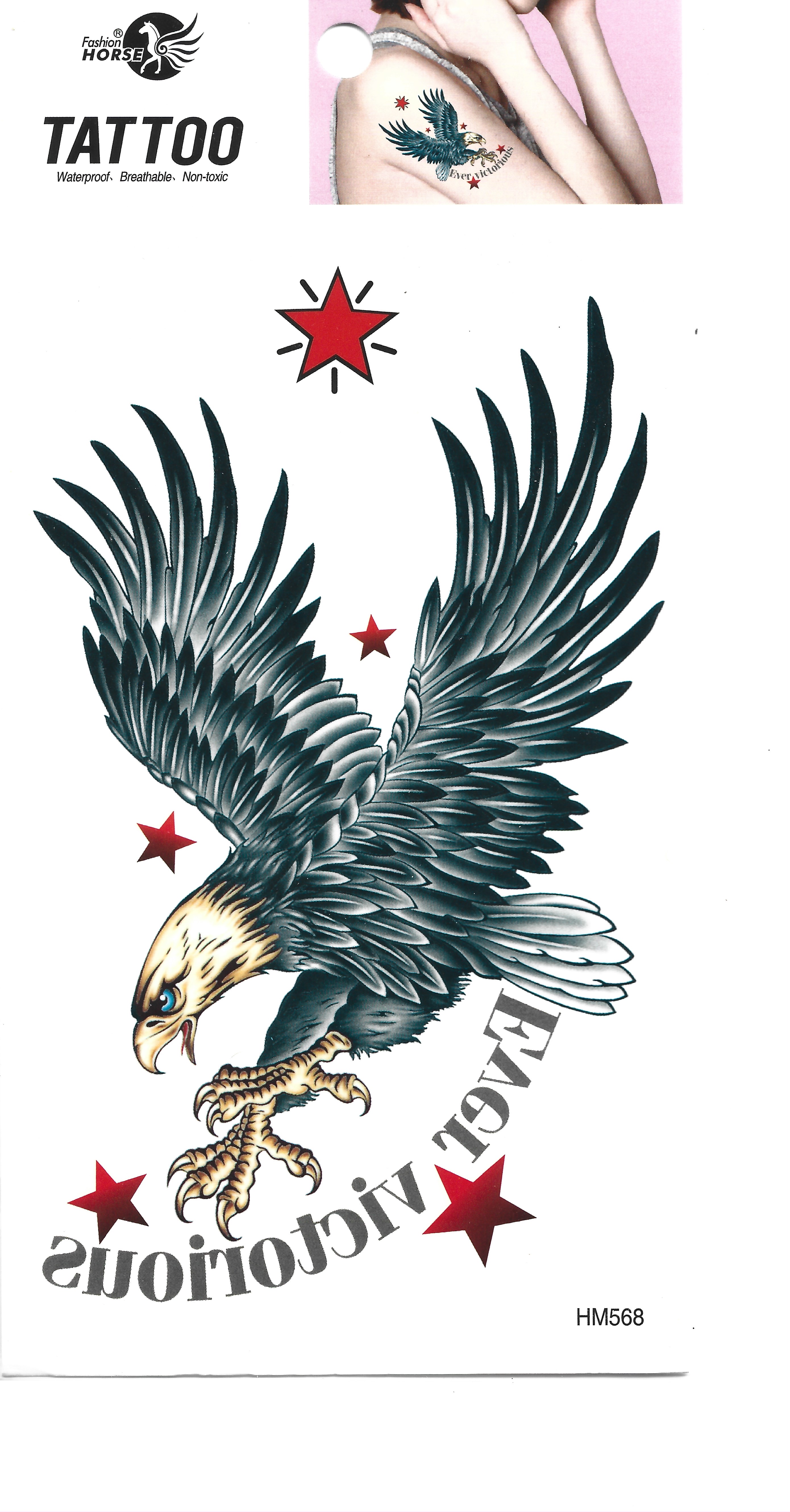 Vista completa de una lámina de tatuaje temporal con un águila grande y detallada con alas extendidas, ojos azules y estrellas rojas. El texto 'EAGLE VICTORIOUS' está debajo del águila, reflejado. Una pequeña imagen insertada muestra el tatuaje aplicado en el hombro de una persona. La esquina superior izquierda muestra la marca 'TATTOO'.