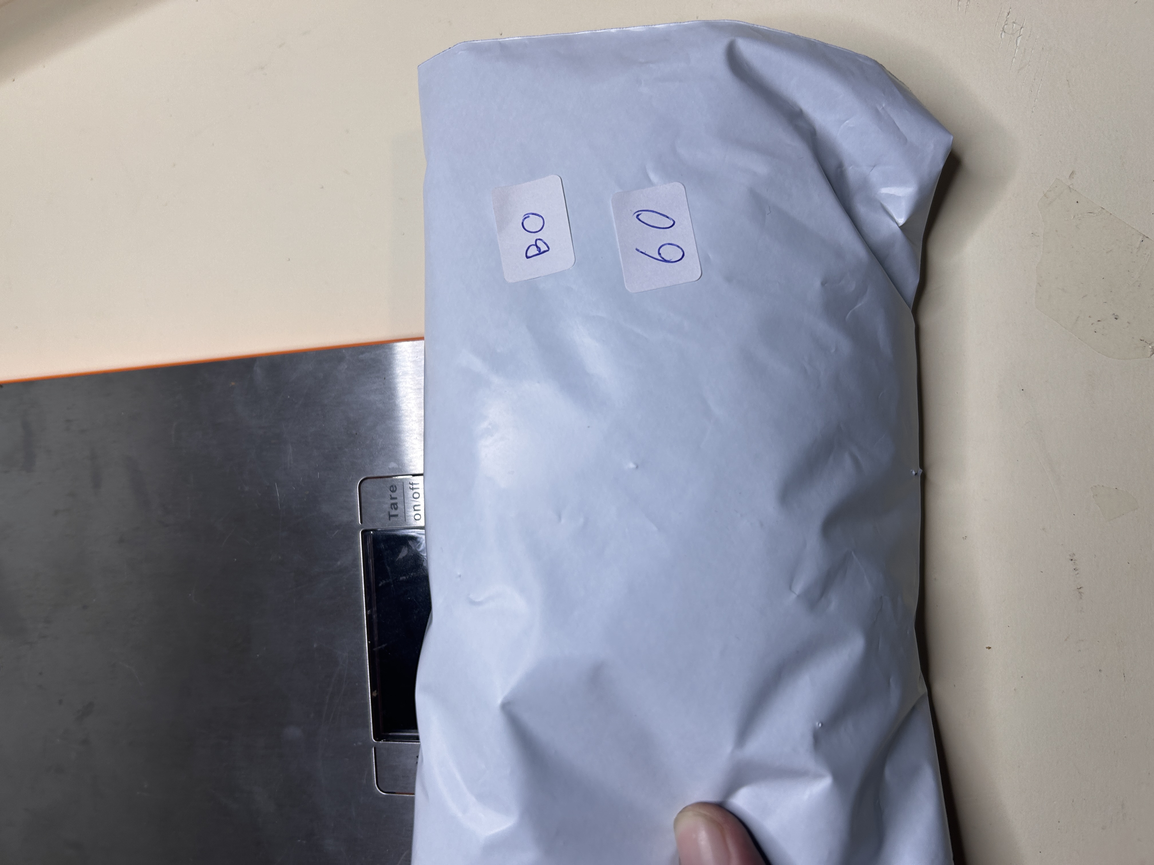 Paquete blanco etiquetado 'BO 60' sobre una báscula, indicando 60 pares de pendientes.