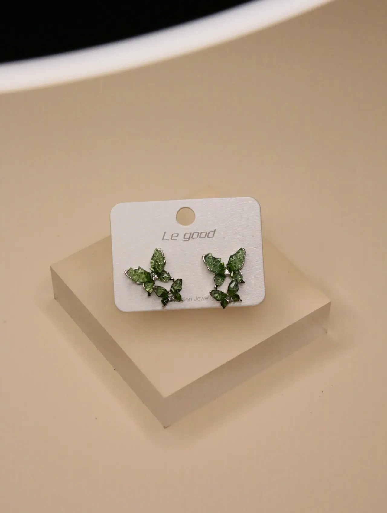 Primer plano de pendientes de tachuela de mariposa verde en una tarjeta de exhibición blanca