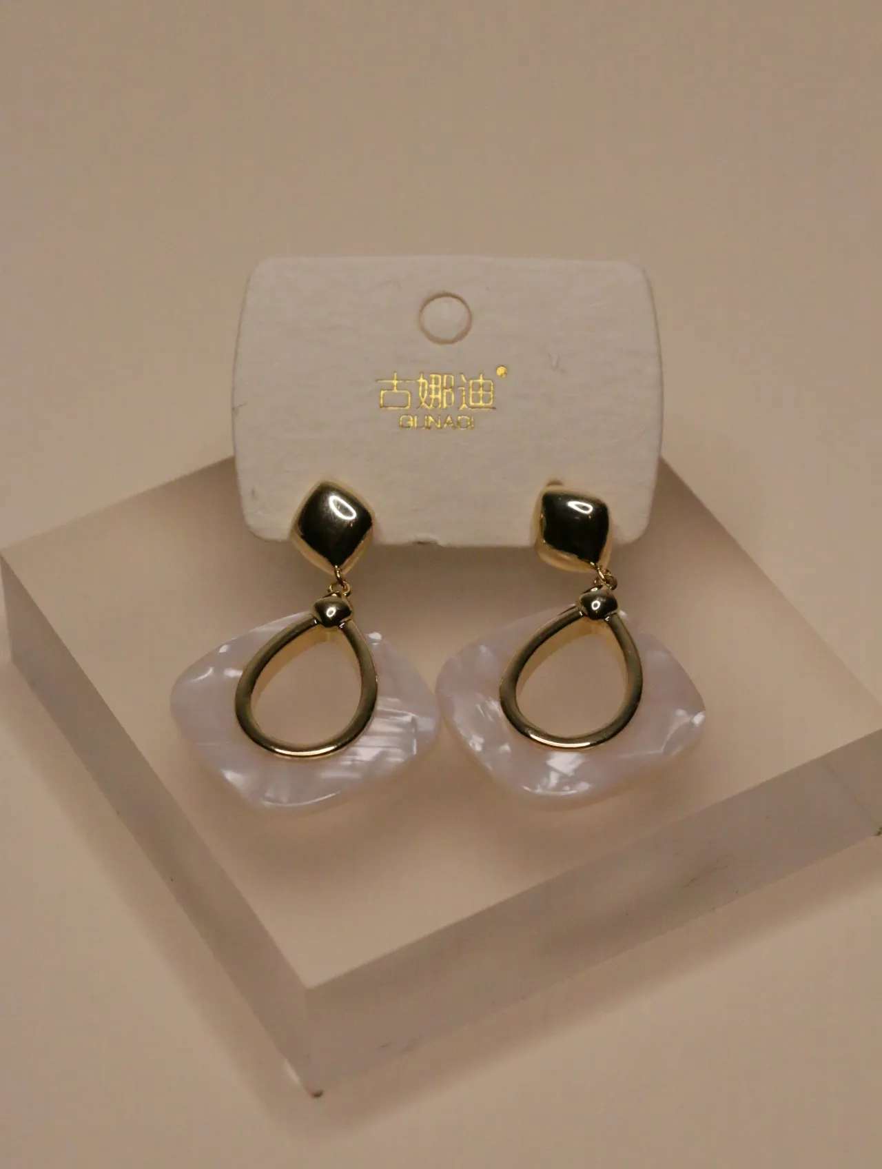Elegantes pendientes geométricos blancos y dorados expuestos