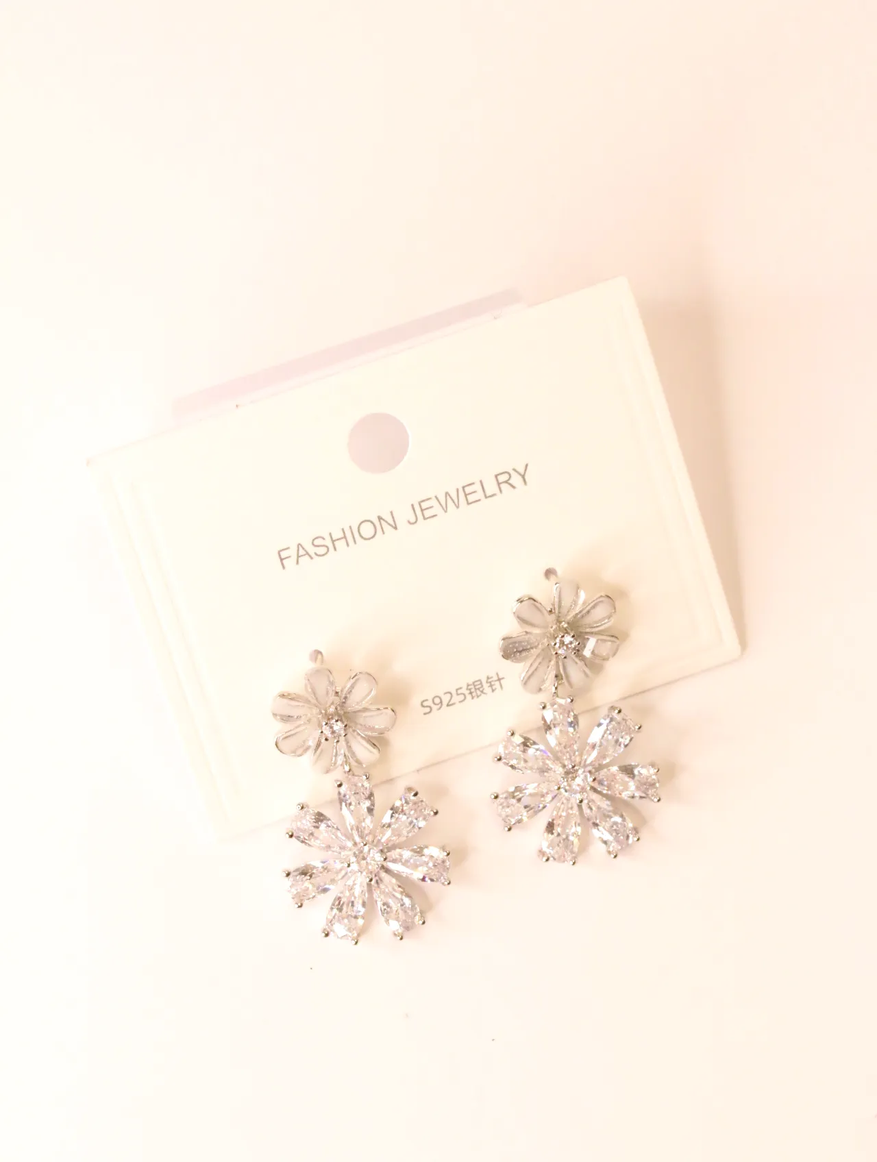 Primer plano de un par de pendientes colgantes de flor con circonitas en una tarjeta — pendientes de moda, vista lateral · Lola y Sol (BO-PD-036)