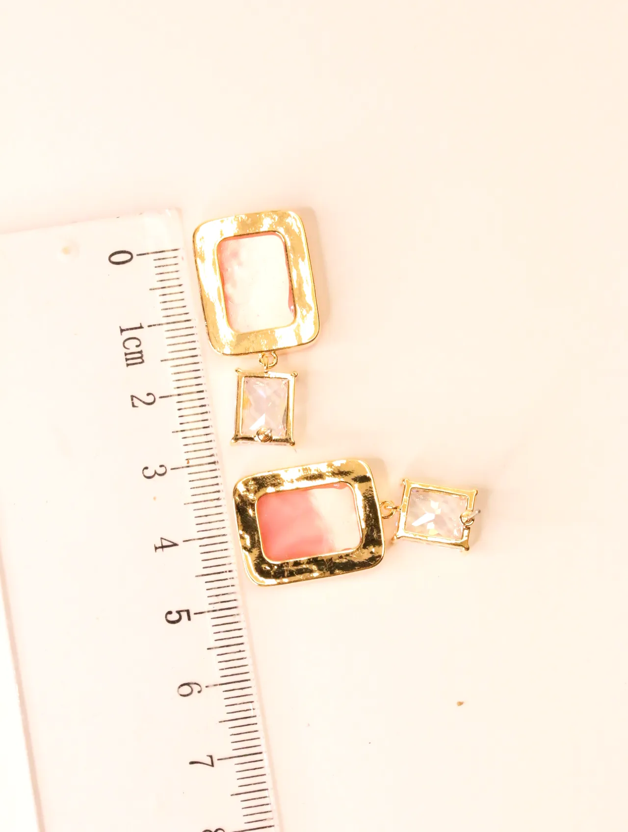 Primer plano de pendientes rectangulares de resina rosa con regla para escala — pendientes baratos, detalle · Lola y Sol (BO-PD-037)