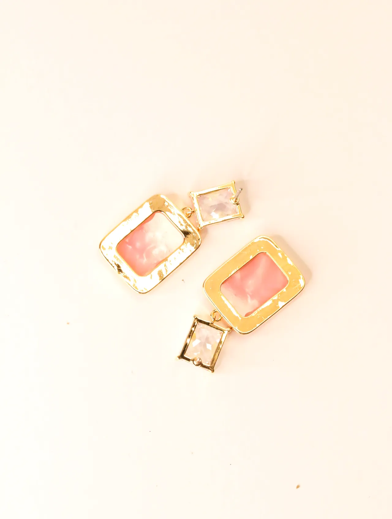 Par de elegantes pendientes colgantes de resina rosa sobre fondo claro — pendientes dorados, primer plano · Lola y Sol (BO-PD-037)