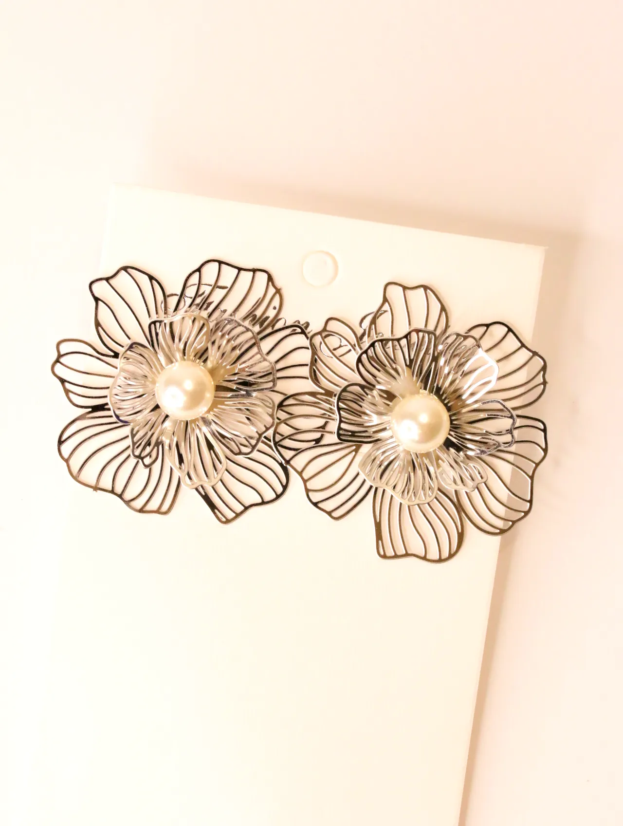 Primer plano de un par de pendientes florales con perla sobre una tarjeta blanca. — pendientes baratos, detalle · Lola y Sol (BO-PD-038)