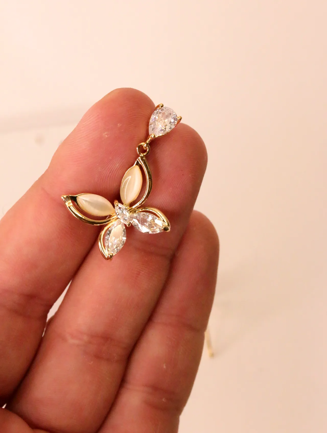 Mano sosteniendo un pendiente de mariposa colgante — pendientes originales, detalle del acabado · Lola y Sol (BO-PD-044)