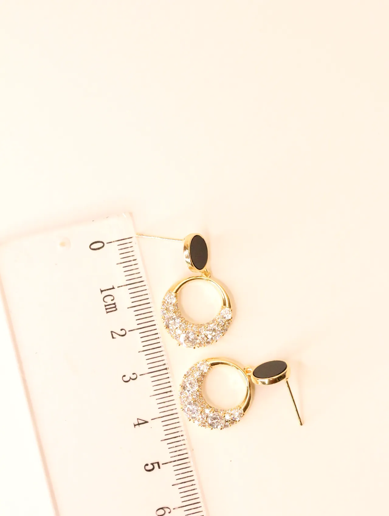 Pendientes de aro brillantes junto a una regla para referencia de tamaño — pendientes dorados, primer plano · Lola y Sol (BO-PD-049)