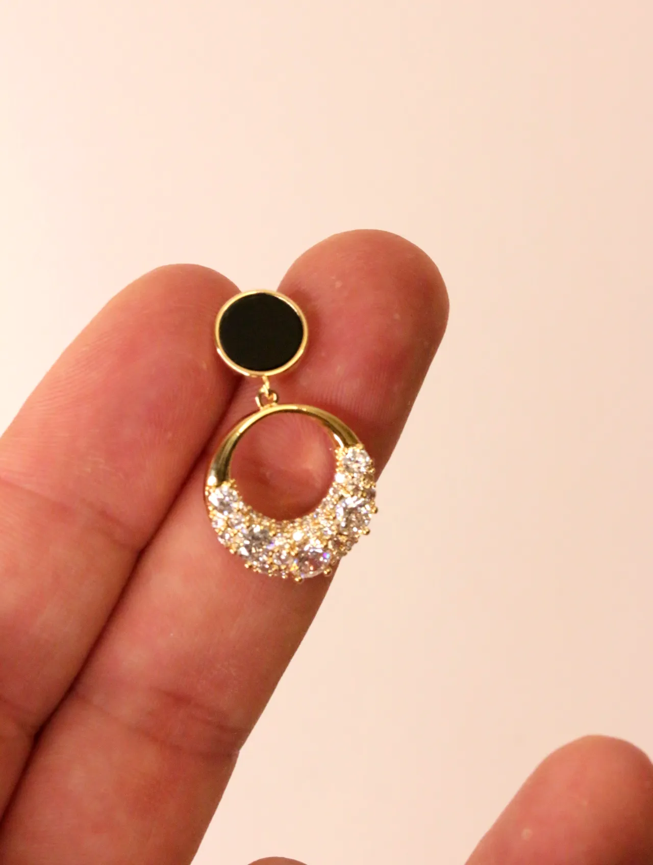Primer plano de un pendiente de aro brillante sostenido entre los dedos — pendientes de moda, vista lateral · Lola y Sol (BO-PD-049)