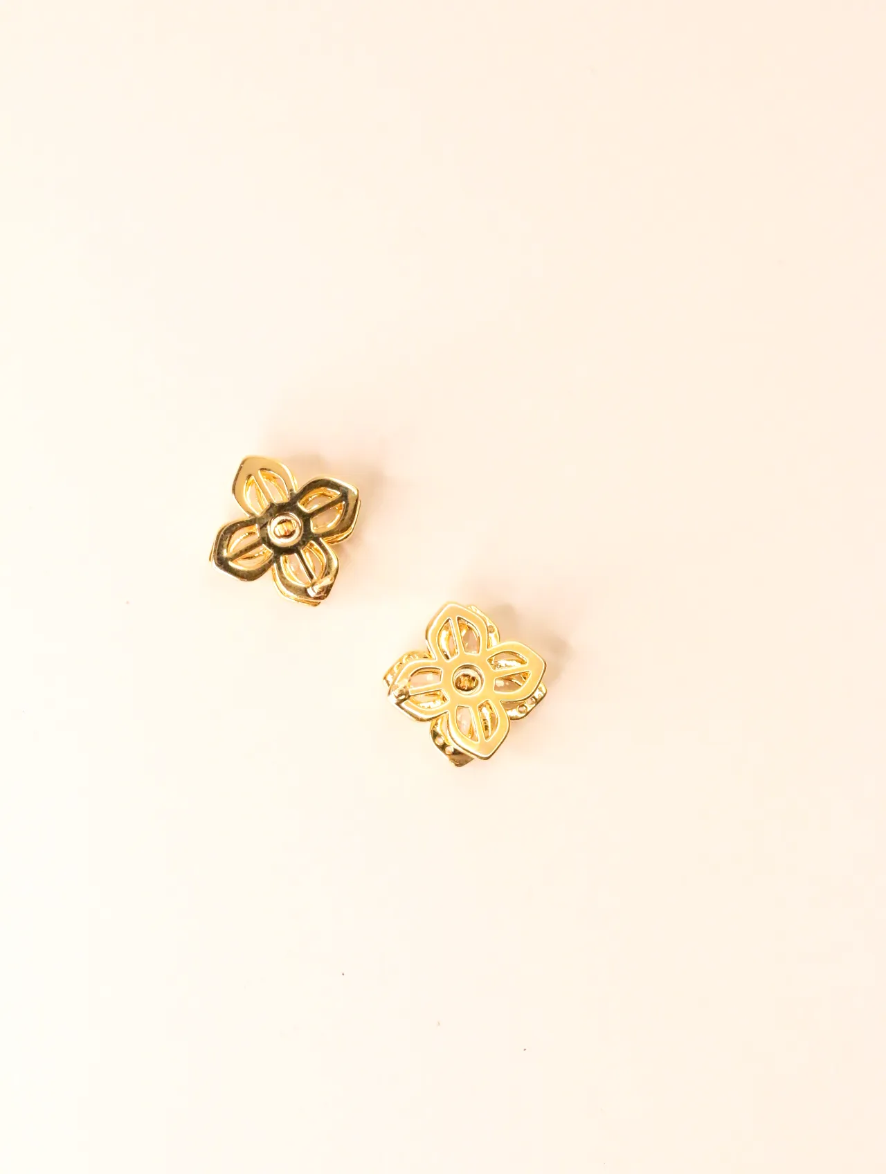 Vista trasera de dos pendientes de trébol tono dorado, mostrando el intrincado trabajo de metal. — pendientes originales, detalle del acabado · Lola y S…