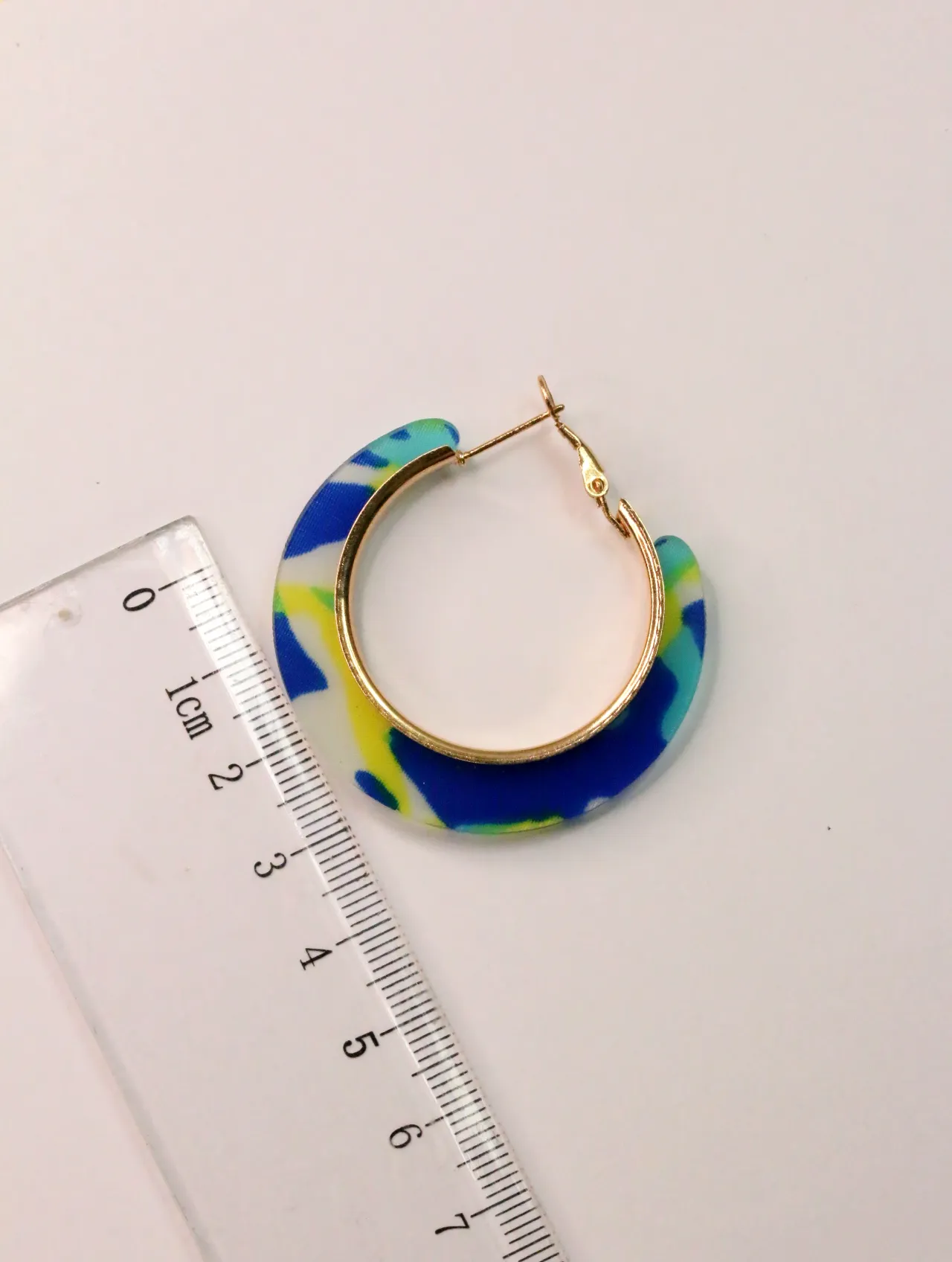 Pendiente de aro multicolor junto a una regla — pendientes baratos, detalle · Lola y Sol (CLR-HPS-001)