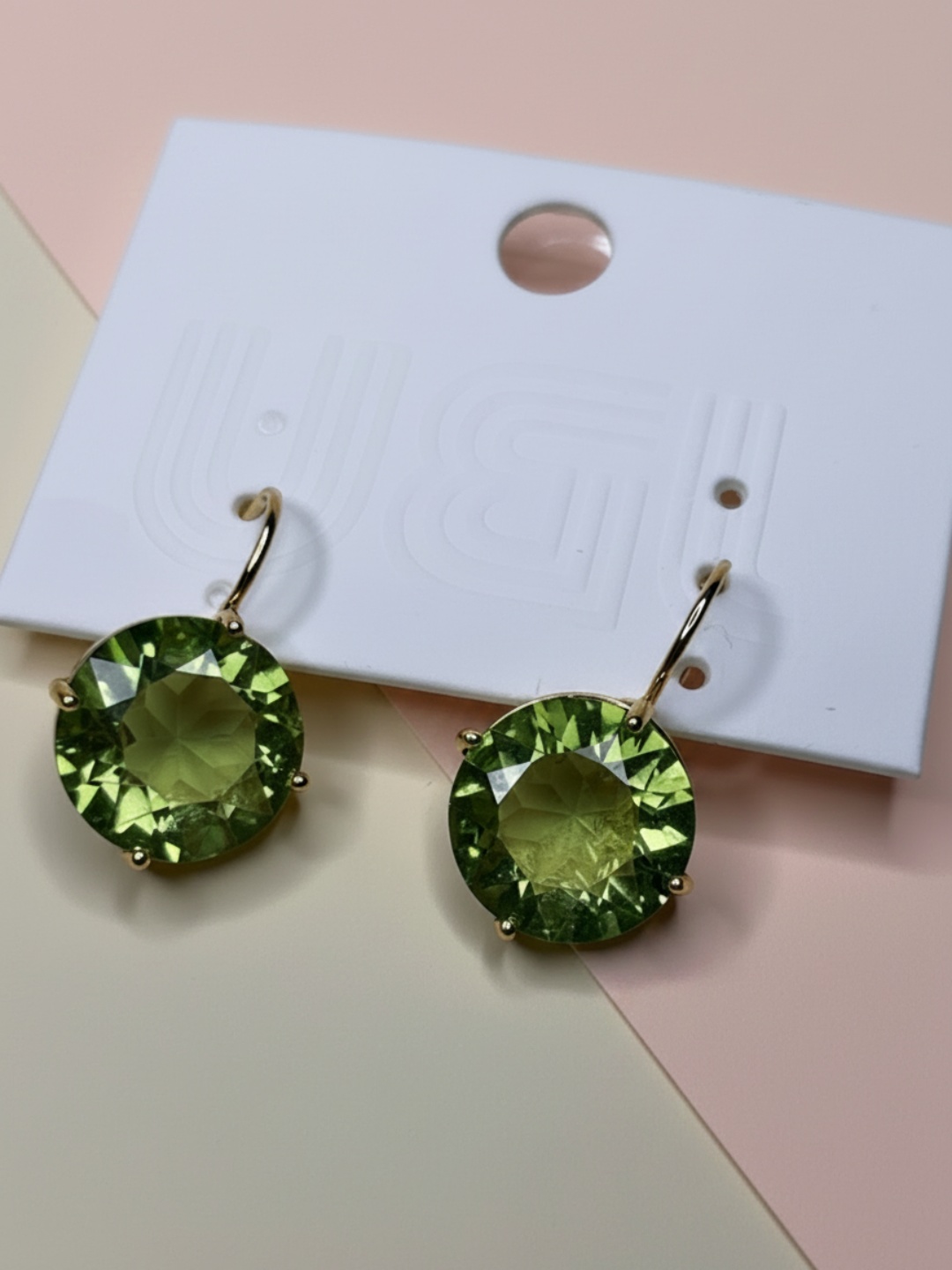 Par de pendientes redondos de piedra verde en tarjeta blanca, primer plano