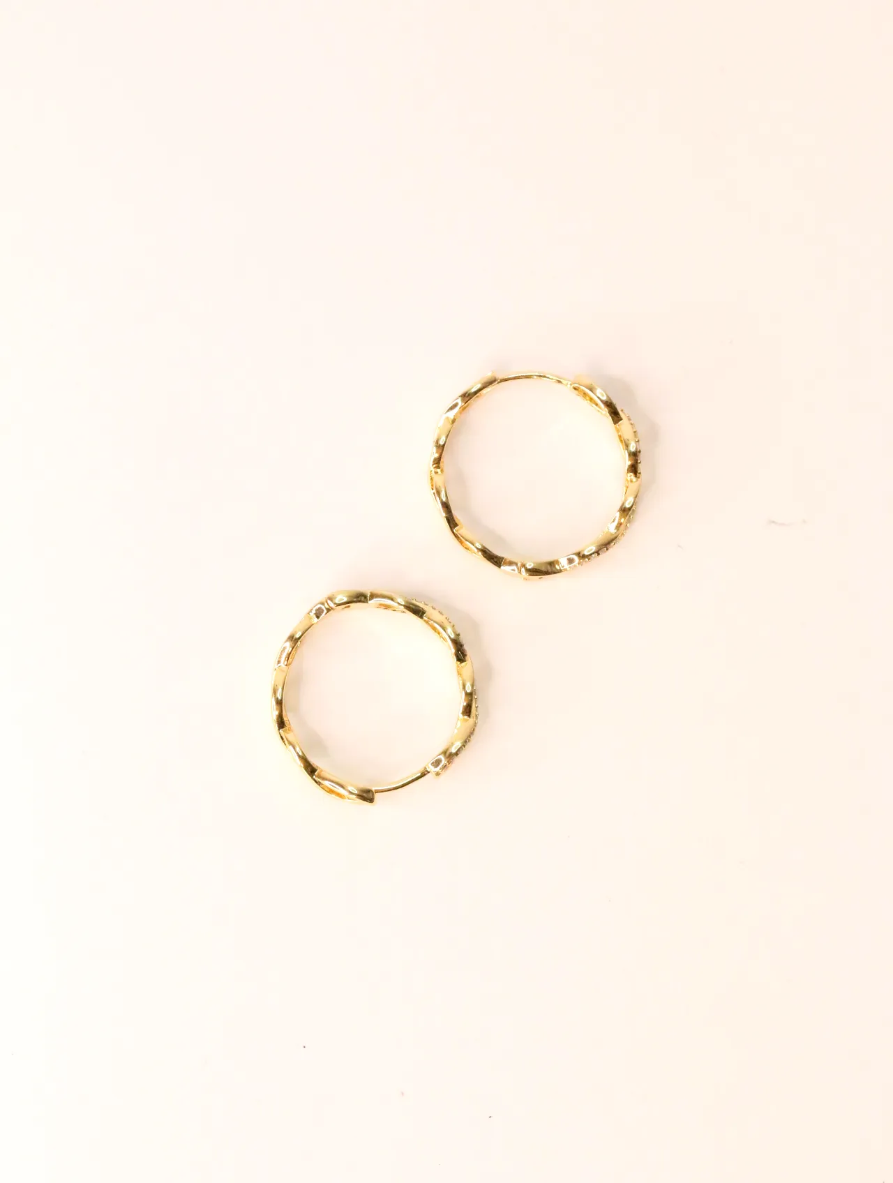 Par de pendientes de aro dorados entrelazados con circonitas sobre fondo liso — pendientes para mujer, vista principal · Lola y Sol (EAR-016)
