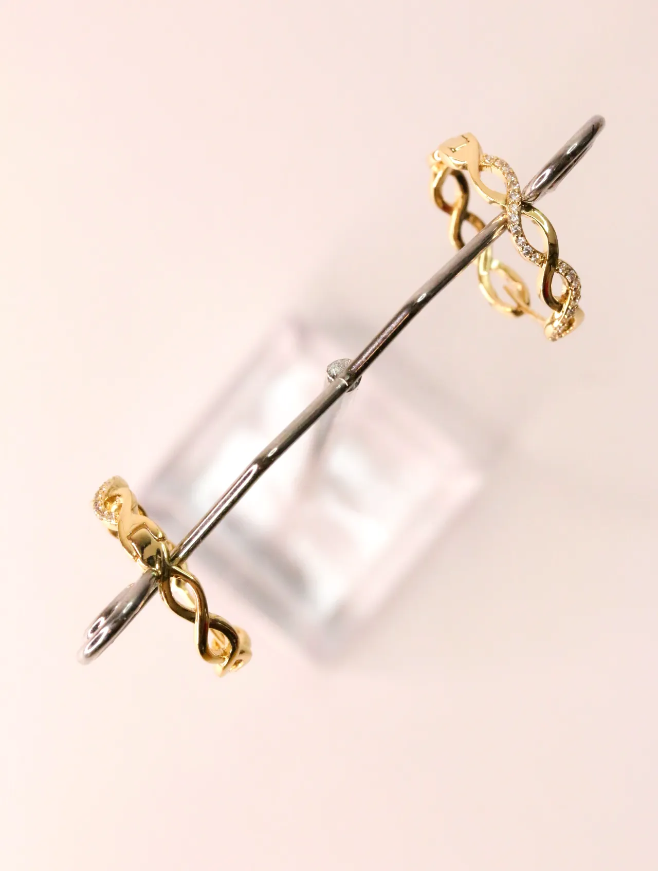 Aros dorados con diseño trenzado y brillo en soporte de exhibición — pendientes de moda, vista lateral · Lola y Sol (EAR-016)