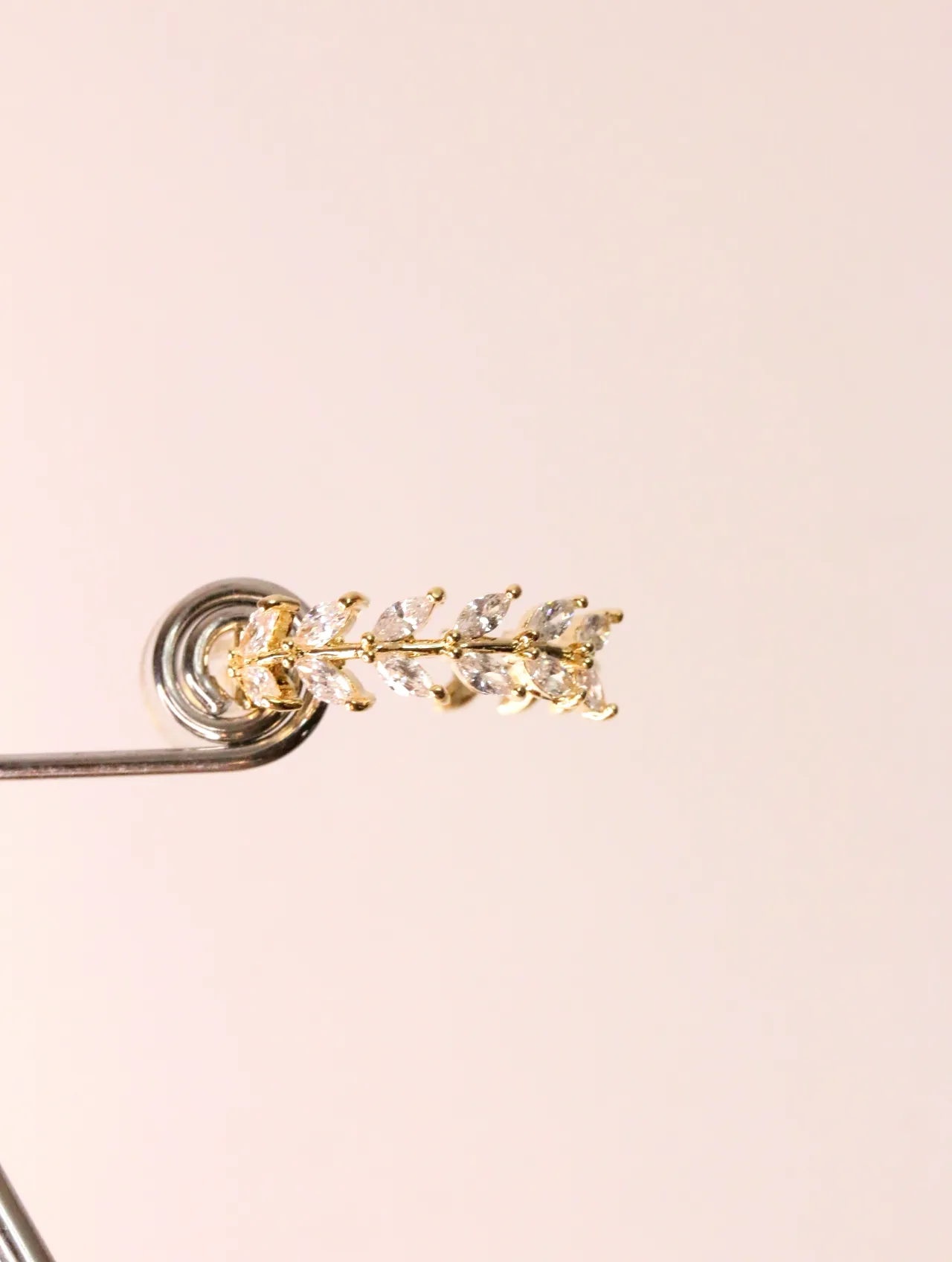 Detalle frontal del pendiente dorado con circonitas en forma de hoja sobre soporte — pendientes baratos, detalle · Lola y Sol (EAR-022)