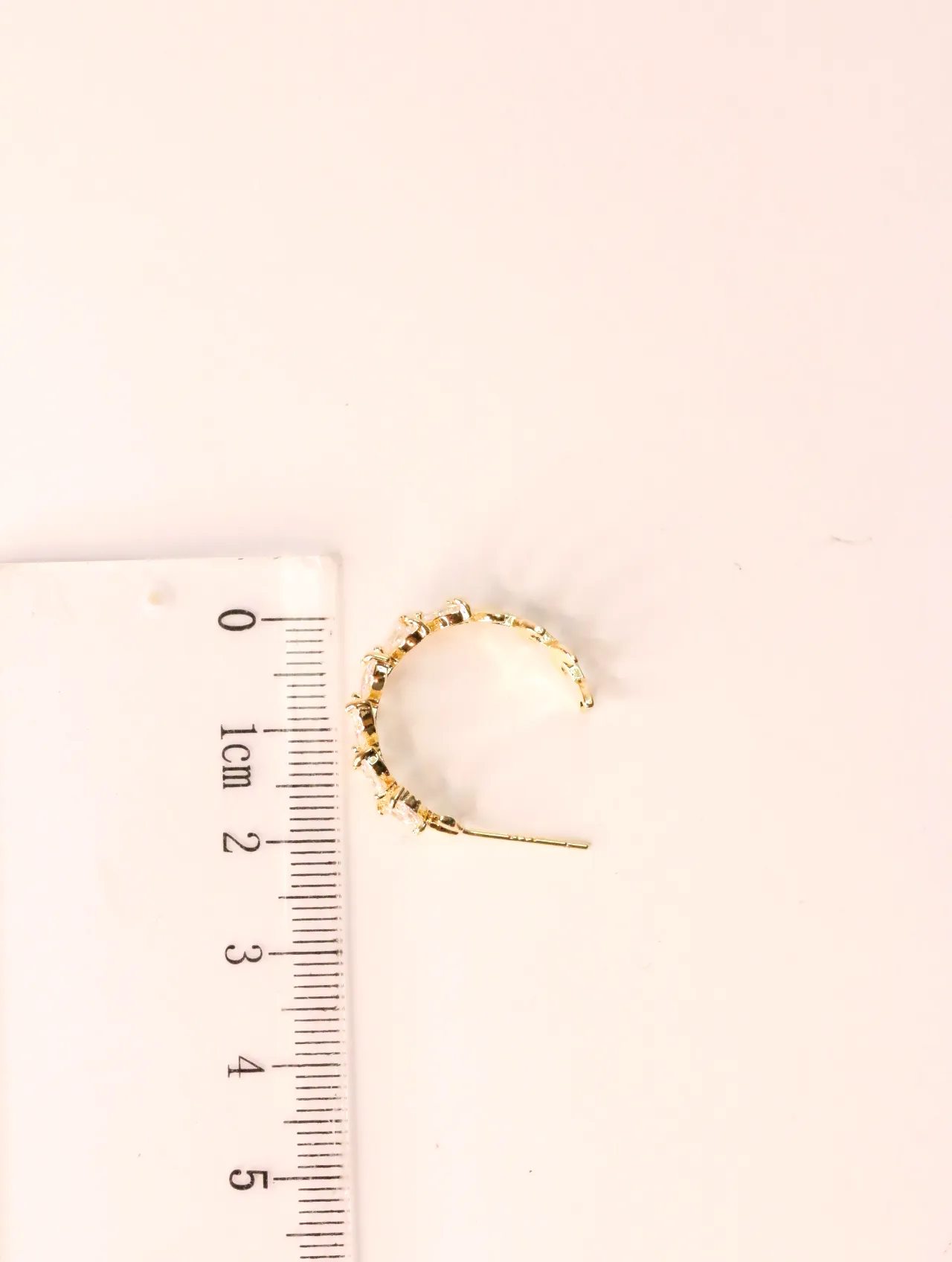 Pendiente dorado con circonitas junto a una regla para ver la medida — pendientes de moda, vista lateral · Lola y Sol (EAR-022)