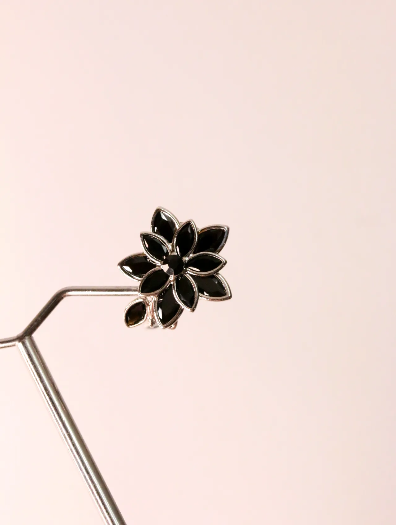 Primer plano de pendiente de flor negra en expositor metálico — pendientes dorados, primer plano · Lola y Sol (EAR-025)