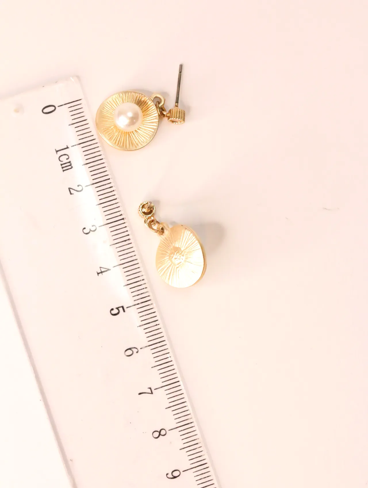 Pendientes dorados con perla junto a una regla para mostrar su tamaño — pendientes baratos, detalle · Lola y Sol (EAR-028)