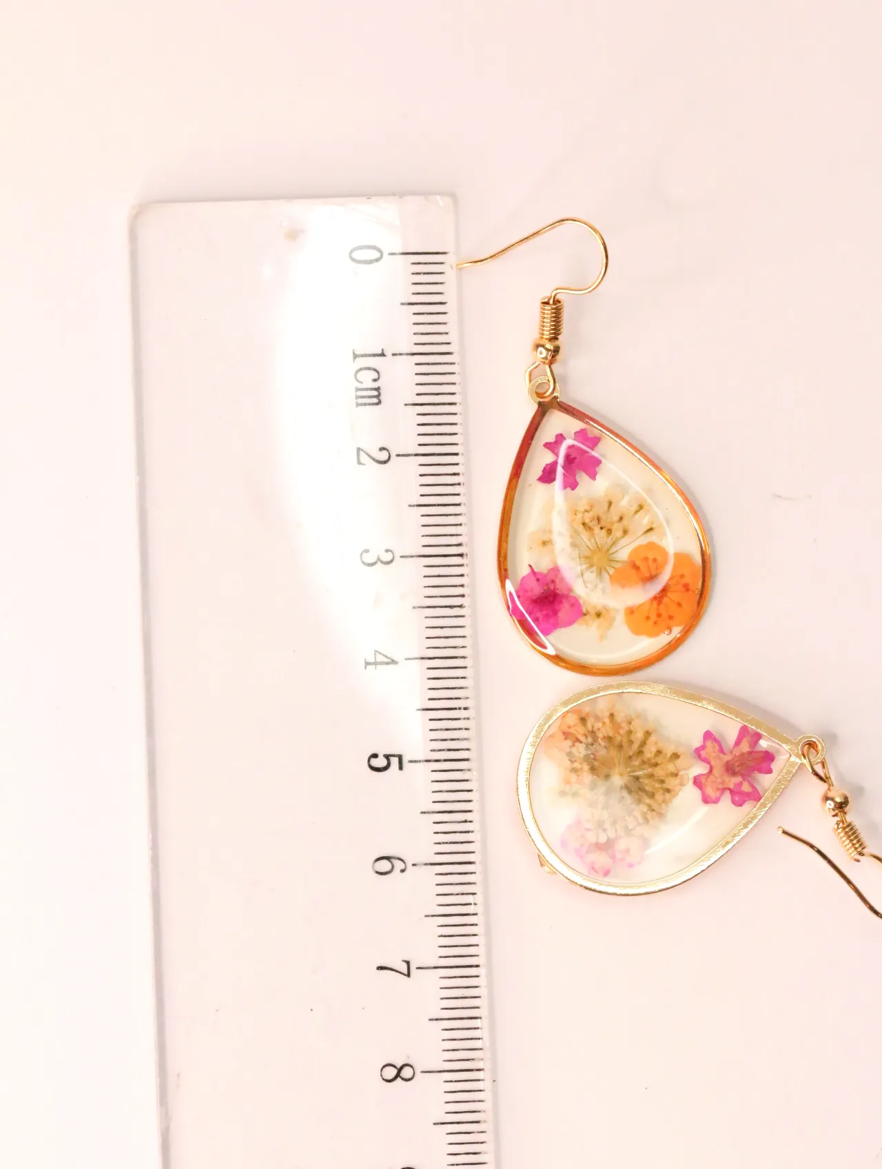 Pendientes de resina con flores secas junto a una regla milimetrada — pendientes baratos, detalle · Lola y Sol (EAR-032)