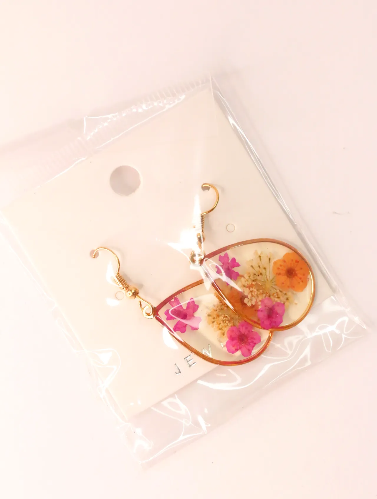 Pendientes de lágrima con flores en resina dentro de su funda protectora — pendientes dorados, primer plano · Lola y Sol (EAR-032)