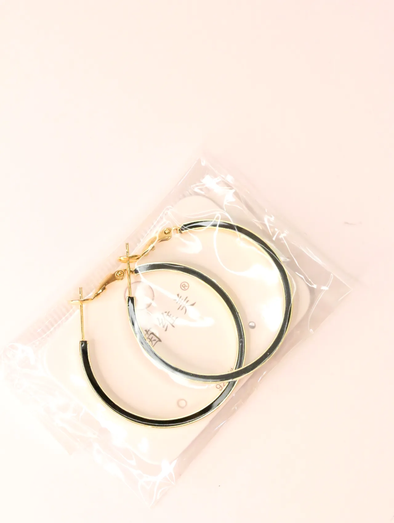 Pendientes de aro dorados y negros en envoltorio transparente — pendientes de moda, vista lateral · Lola y Sol (EAR-033)