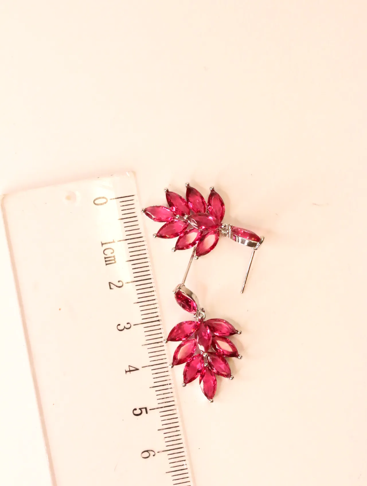 Pendientes de cristales fucsia junto a una regla milimetrada para referencia de medida — pendientes dorados, primer plano · Lola y Sol (EAR-041)
