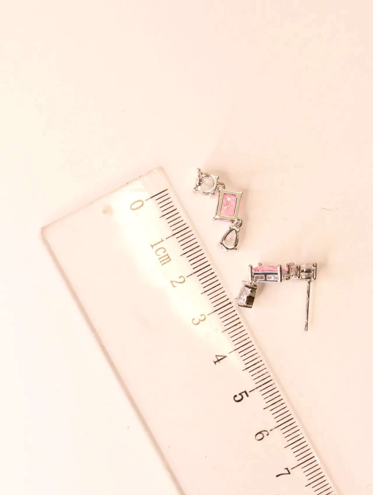 Pendientes plateados con cristal rosa junto a una regla graduada — pendientes para mujer, vista principal · Lola y Sol (EAR-046)