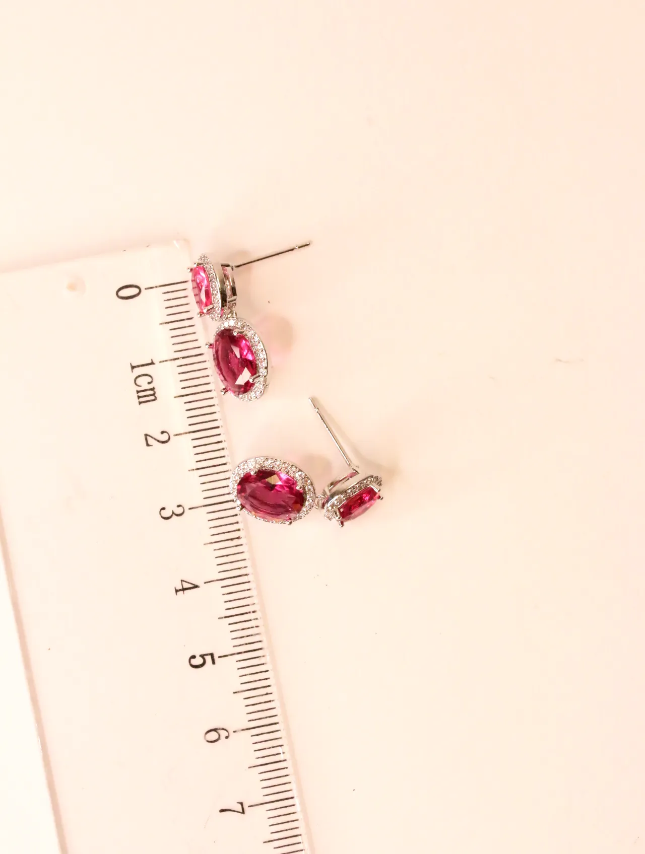 Pendientes con gemas fucsia junto a una regla — pendientes baratos, detalle · Lola y Sol (EAR-048)