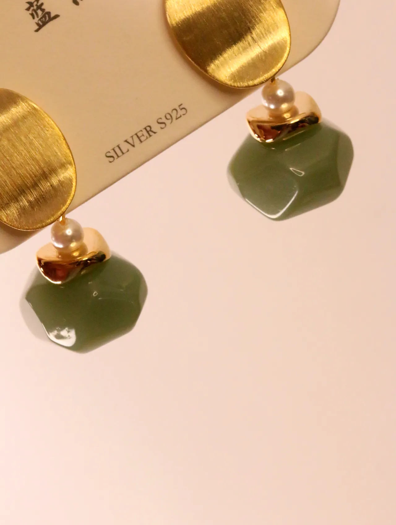 Primer plano de los pendientes dorados y verde salvia sobre tarjeta de presentación — pendientes para mujer, vista principal · Lola y Sol (EAR-050)