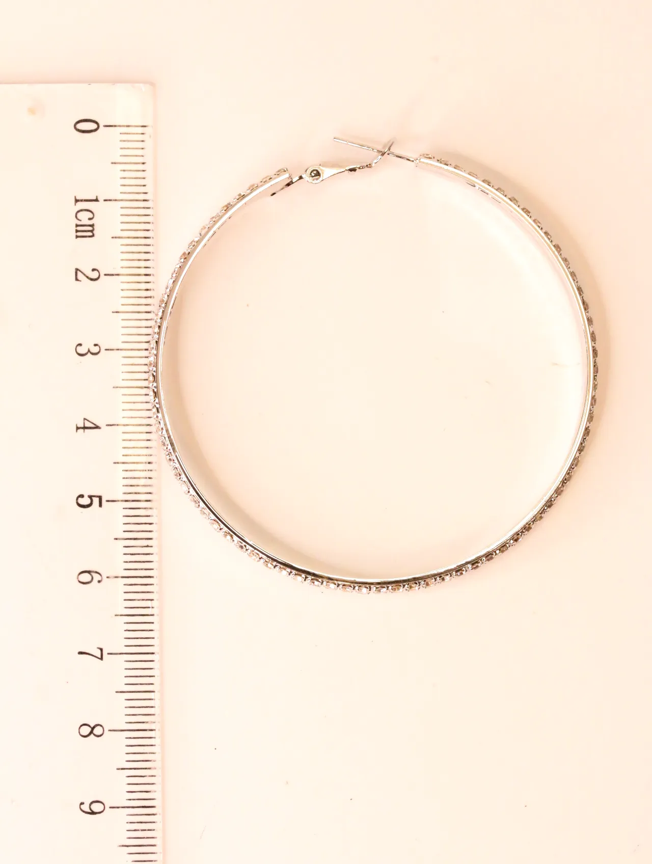 Pendiente de aro plateado con strass junto a una regla — pendientes para mujer, vista principal · Lola y Sol (EAR-052)
