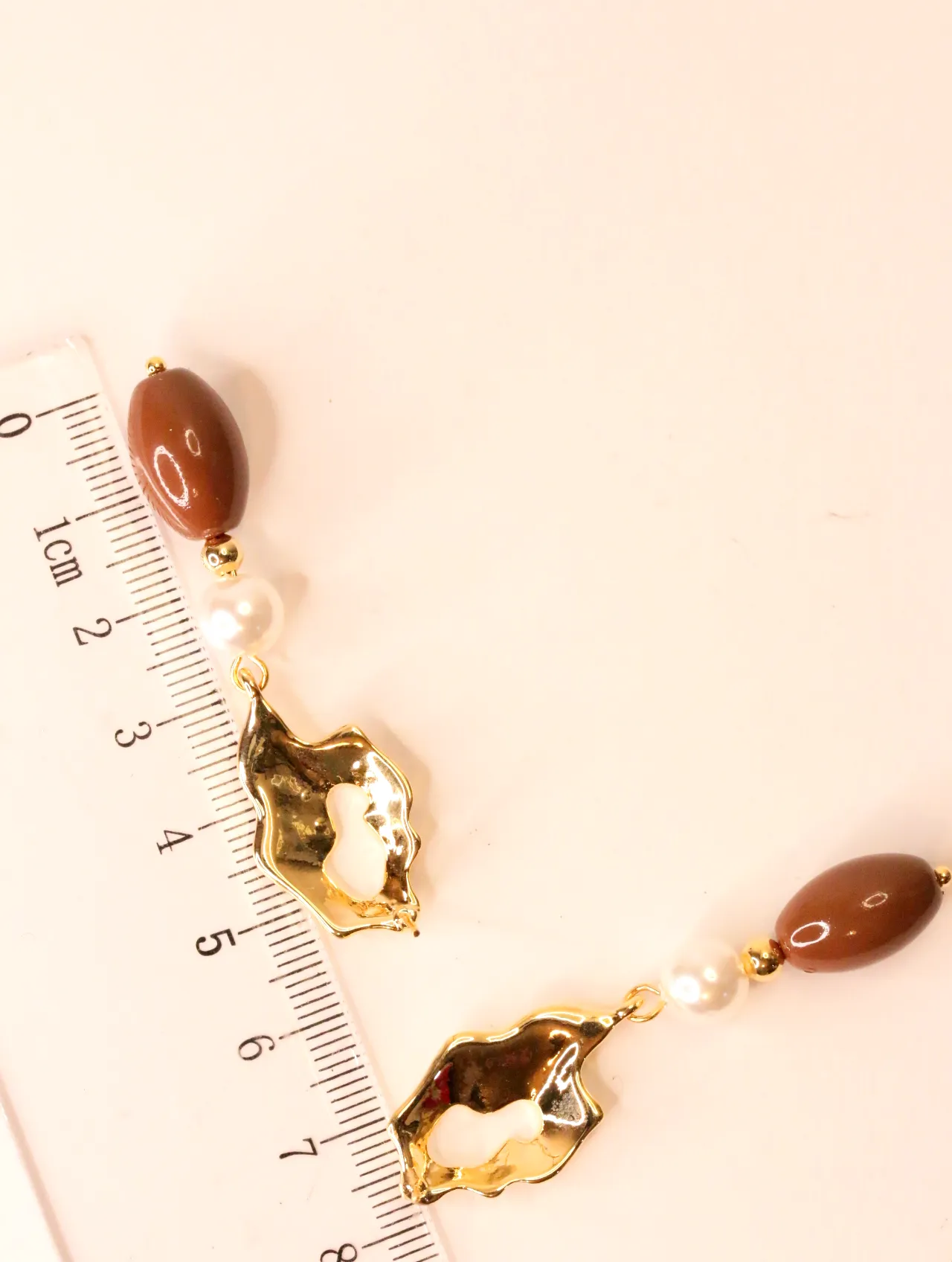 Pendientes colgantes dorados junto a una regla para apreciar su longitud — pendientes de moda, vista lateral · Lola y Sol (EAR-058)