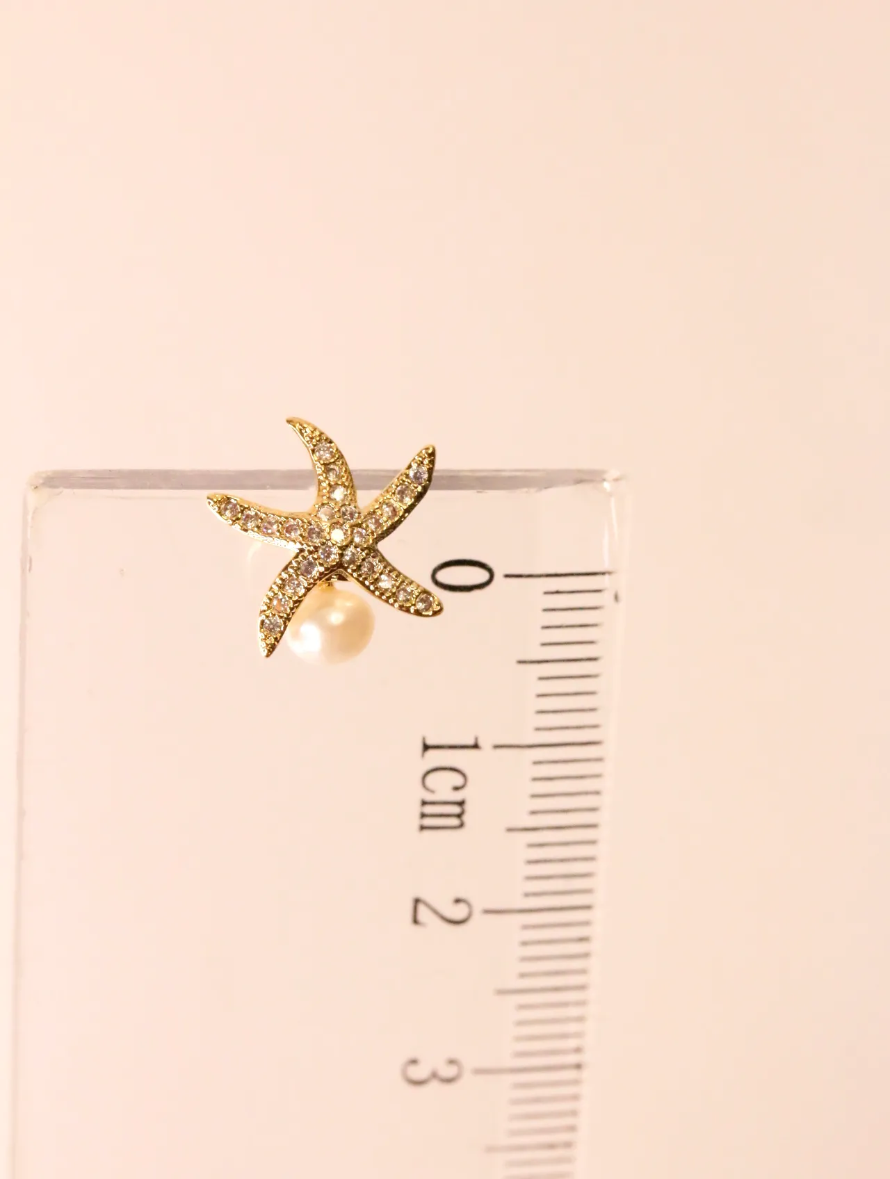 Pendiente de estrella de mar junto a una regla de medición — pendientes baratos, detalle · Lola y Sol (EAR-062)
