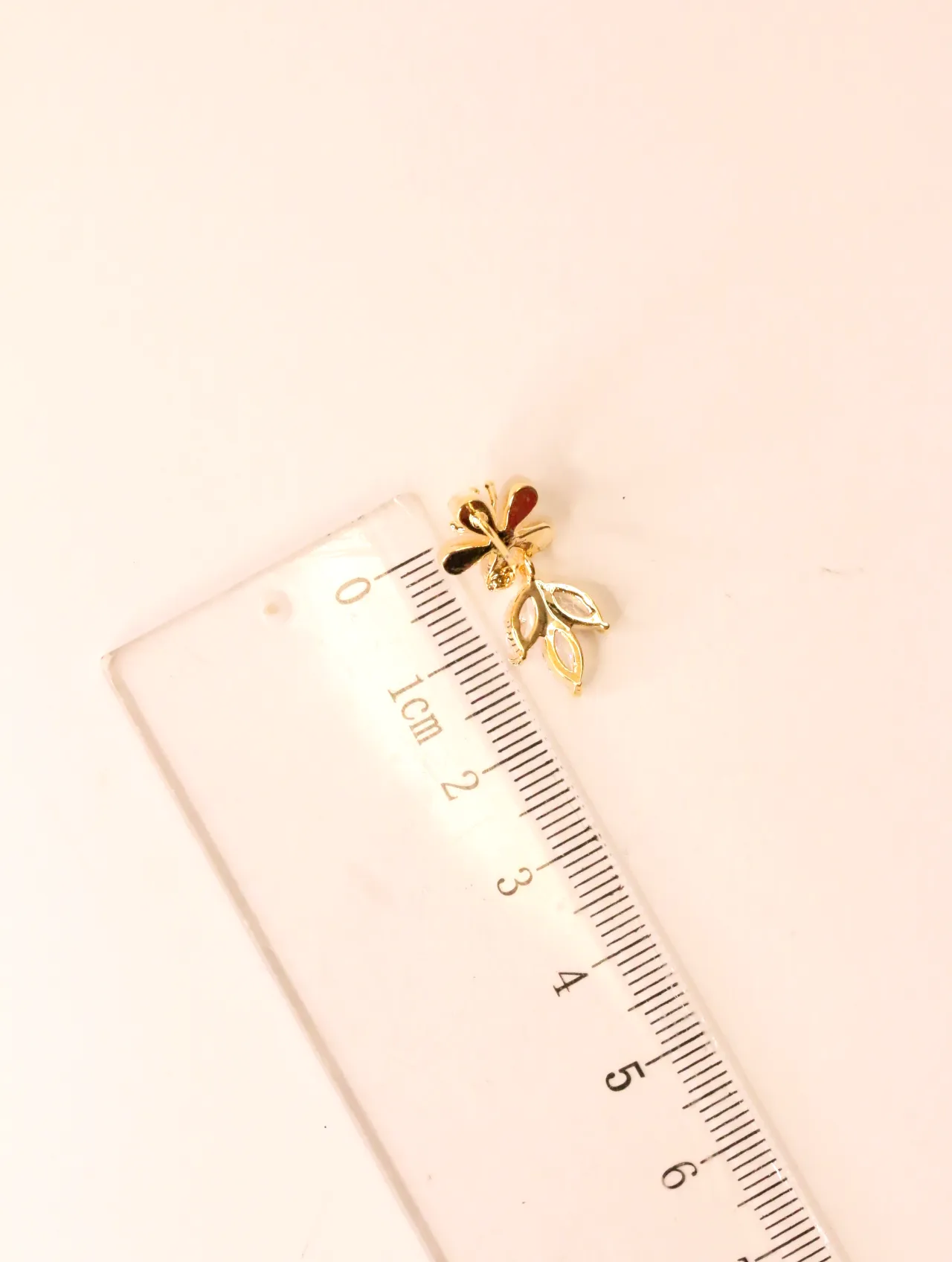 Reverso del pendiente floral junto a una regla milimétrica — pendientes de moda, vista lateral · Lola y Sol (EAR-063)