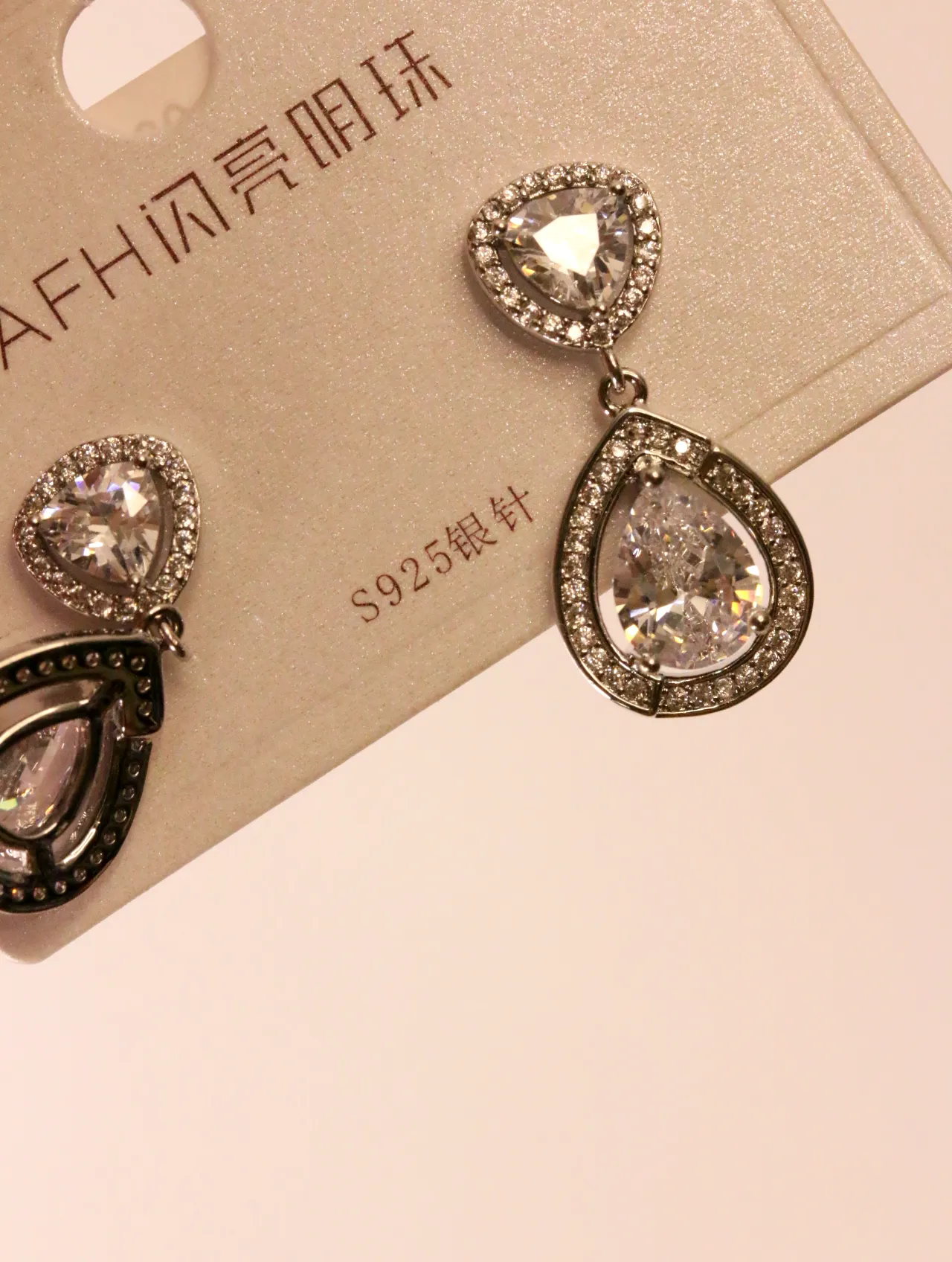 Detalle de cerca de los pendientes de cristal sobre su cartón — pendientes de moda, vista lateral · Lola y Sol (EAR-066)