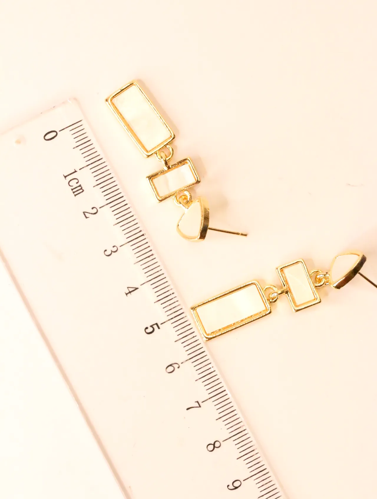 Pendientes dorados geométricos junto a una regla de medir — pendientes para mujer, vista principal · Lola y Sol (EAR-067)