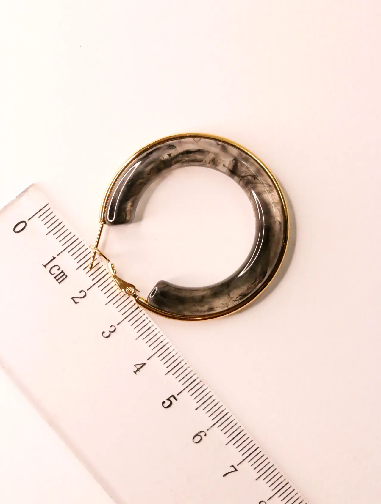 Pendiente de aro en resina junto a regla medidora en centímetros — pendientes originales, detalle del acabado · Lola y Sol (EAR-071)