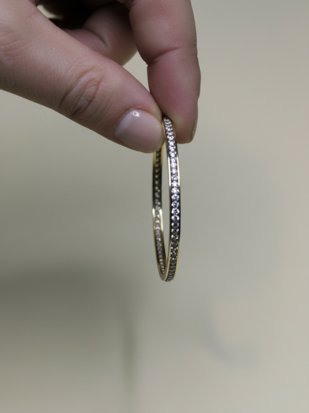Detalle de pendiente de aro dorado con strass sostenido con la mano — pendientes para mujer, vista principal · Lola y Sol (EAR-086)