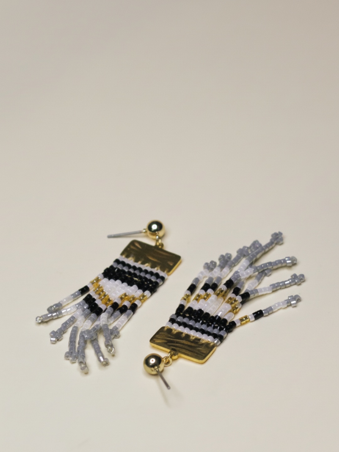 Pendientes dorados con flecos de cuentas negras, blancas y translúcidas — pendientes de moda, vista lateral · Lola y Sol (EAR-089)