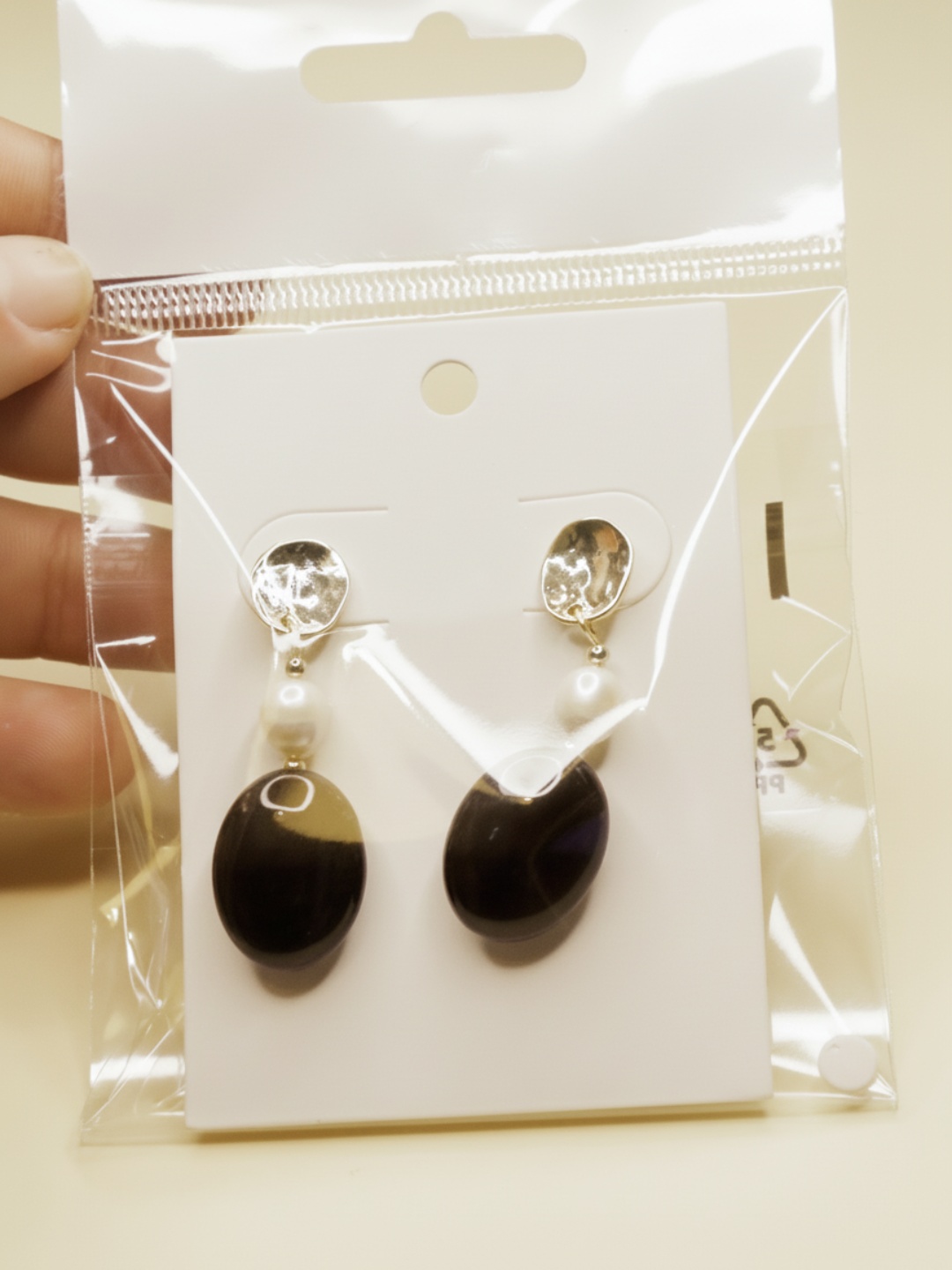 Pendientes colgantes negros sobre tarjeta dentro de un envoltorio transparente — pendientes de moda, puestos en la oreja · Lola y Sol (EAR-099)