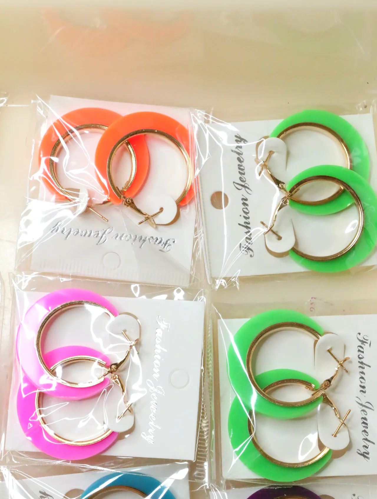 Pendientes de aro naranjas, verdes y rosas en tarjetas — lote de bisutería originales, detalle del acabado · Lola y Sol (H0007)