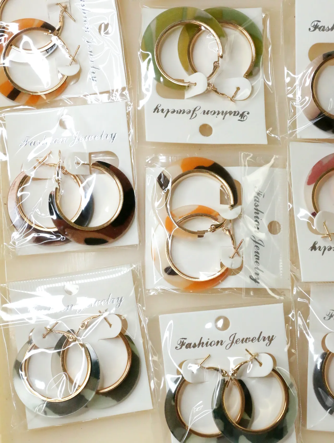 Aros estampados variados sobre soportes expositores — lote de bisutería baratos, detalle · Lola y Sol (H0009)