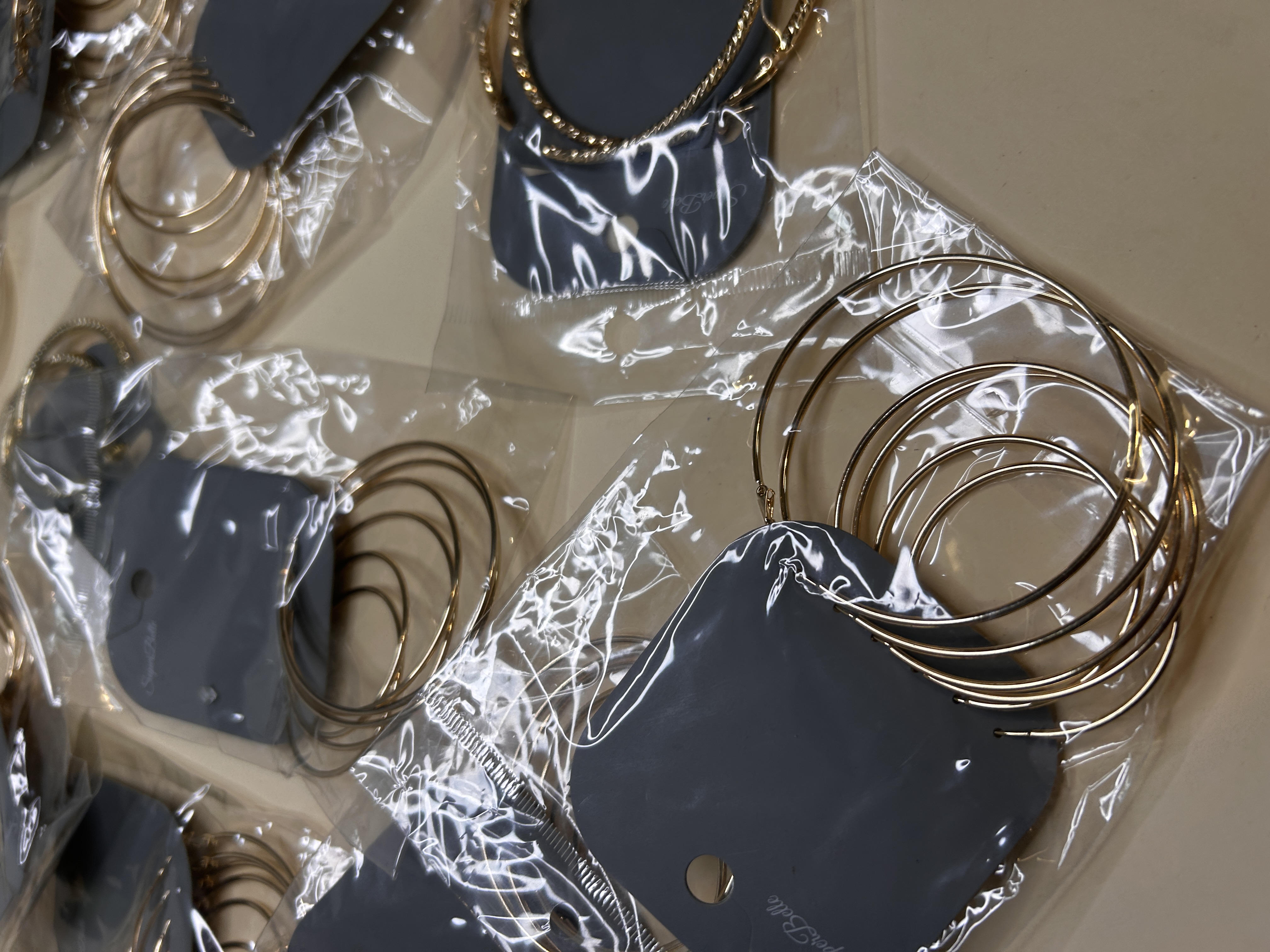 Primer plano de pendientes de aro dorados sobre tarjetas grises — lote de pendientes dorados, primer plano · Lola y Sol (HOOP-203)